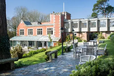 a building with a table and chairs in a garden at Hotel Meudon in Falmouth