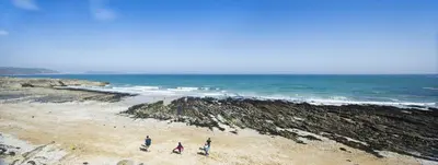 three people walking on a beach near the ocean at Hotel Meudon in Falmouth