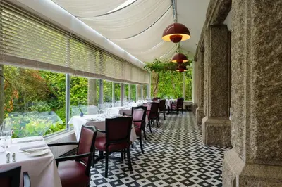 a restaurant with white tables and chairs and windows at Hotel Meudon in Falmouth