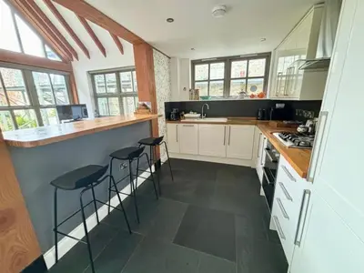 a kitchen with white cabinets and bar stools at The Engine House in Truro