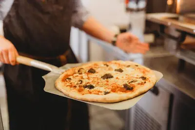 a person holding a pizza on top of a counter at Hotel VARA in Truro