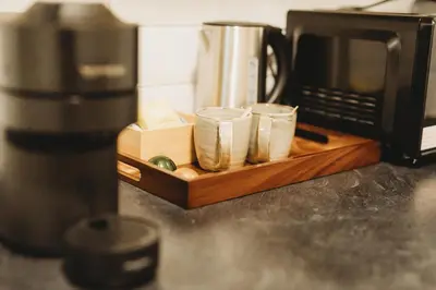 a wooden tray with four drinking glasses next to a microwave at Hotel VARA in Truro