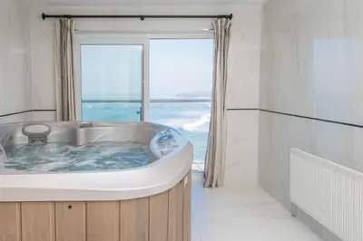 a bath tub in a room with a large window at Fistral Beach Hotel and Spa - Adults Only in Newquay
