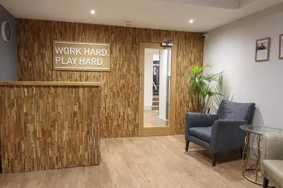 a lobby with a work hard play hard sign on a wall at Fistral Beach Hotel and Spa - Adults Only in Newquay