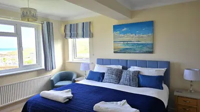 a bedroom with a blue and white bed and a window at Fairlee in Perranporth