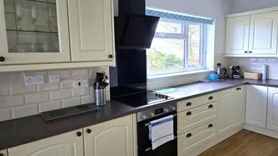 a kitchen with white cabinets and a black stove top oven at Fairlee in Perranporth