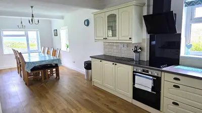 a kitchen with white cabinets and a table with a stove at Fairlee in Perranporth