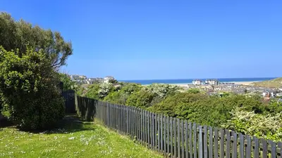 a fence on a hill with the ocean in the background at Fairlee in Perranporth