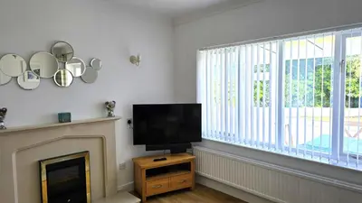 a living room with a fireplace and a flat screen tv at Fairlee in Perranporth