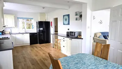 a kitchen with white cabinets and a black refrigerator at Fairlee in Perranporth