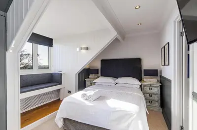 a white bedroom with a bed and a window at Bosanneth in Falmouth