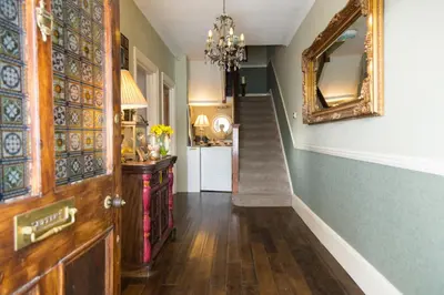 a hallway with a door and a mirror and a staircase at Bosanneth in Falmouth