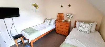 a bedroom with two beds and a tv and a dresser at Sand Dunes in Perranporth