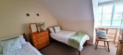 a bedroom with two beds and a dresser and a window at Sand Dunes in Perranporth