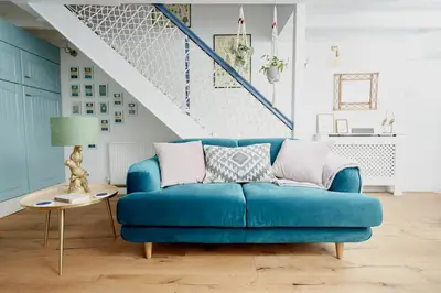 a blue couch in a living room with a staircase at Poachers Pocket Cottage in Bodmin