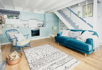 a living room with a blue couch and a kitchen at Poachers Pocket Cottage in Bodmin