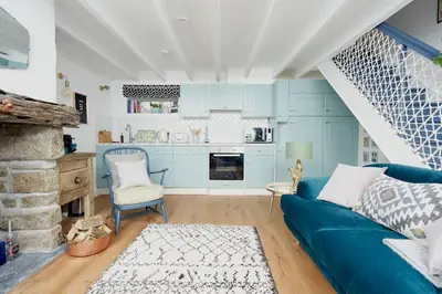 a living room with a blue couch and a kitchen at Poachers Pocket Cottage in Bodmin