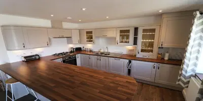 a kitchen with white cabinets and a wooden counter top at Yachtsmans Rest in Falmouth