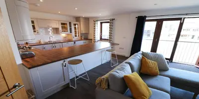 a living room with a couch and a kitchen at Yachtsmans Rest in Falmouth
