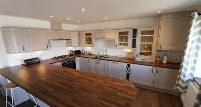 a kitchen with white cabinets and a wooden counter top at Yachtsmans Rest in Falmouth