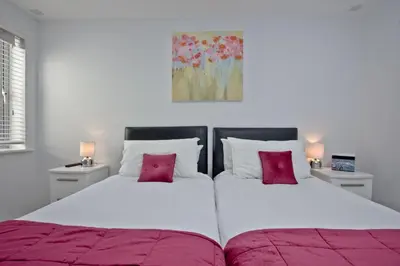two beds in a bedroom with two pink pillows at 5 Fistral Beach, Newquay in Newquay