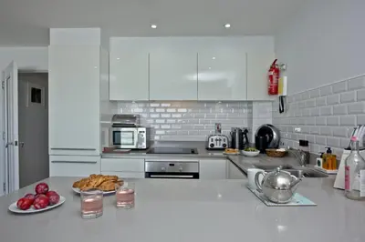 a kitchen with white cabinets and a plate of food on a counter at 5 Fistral Beach, Newquay in Newquay