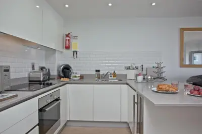 a kitchen with white cabinets and a plate of food at 5 Fistral Beach, Newquay in Newquay