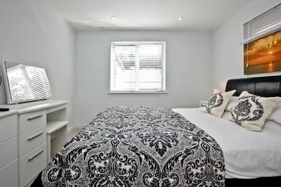 a white bedroom with a bed with a black and white blanket at 5 Fistral Beach, Newquay in Newquay