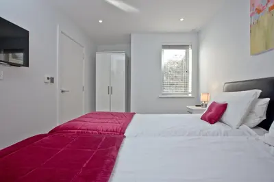 a large white bed with a red blanket on it at 5 Fistral Beach, Newquay in Newquay