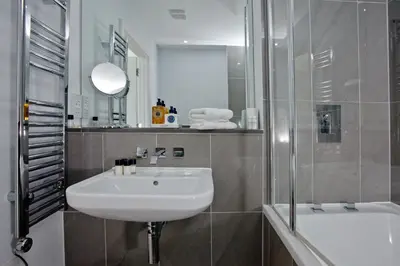 a bathroom with a sink and a shower and a tub at 5 Fistral Beach, Newquay in Newquay