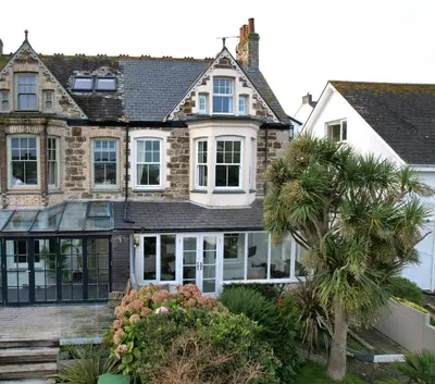 a house with white windows and a palm tree at Michaelstow in Perranporth