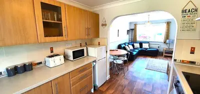 a kitchen and a living room with a couch at 7 Penhale in Perranporth