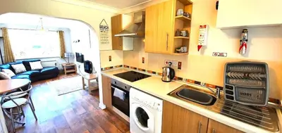 a kitchen and living room with a washer and dryer at 7 Penhale in Perranporth