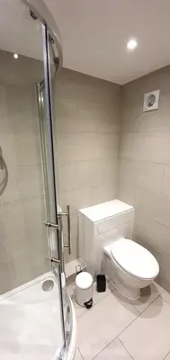 a white bathroom with a toilet and a shower at 7 Penhale in Perranporth