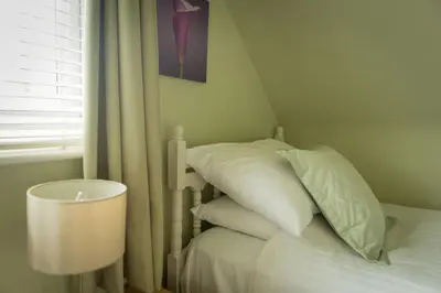 a bed with white pillows and a lamp next to a window at Warwick Lodge in Perranporth