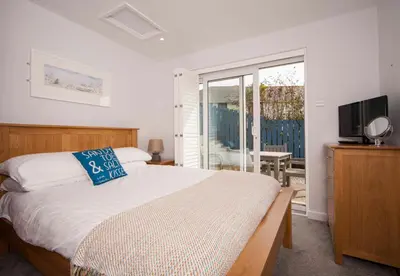 a bedroom with a large bed and a television at Mawgan Porth Apartments in Mawgan Porth