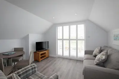 a living room with a couch and a table and a television at Mawgan Porth Apartments in Mawgan Porth