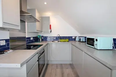 a kitchen with white cabinets and a microwave at Mawgan Porth Apartments in Mawgan Porth