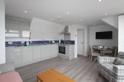 a kitchen and living room with a couch and a table at Mawgan Porth Apartments in Mawgan Porth