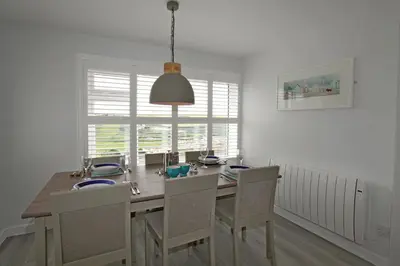 a dining room with a wooden table and chairs at Mawgan Porth Apartments in Mawgan Porth
