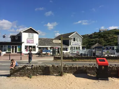a group of buildings on a beach with a man and a child at Mawgan Porth Apartments in Mawgan Porth