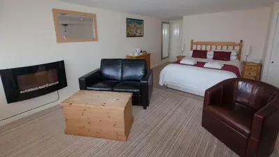 a bedroom with a bed and a chair and a television at King Arthurs Arms in Tintagel