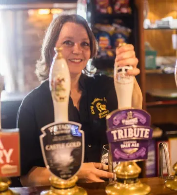 a woman holding up a drink in a bar at King Arthurs Arms in Tintagel