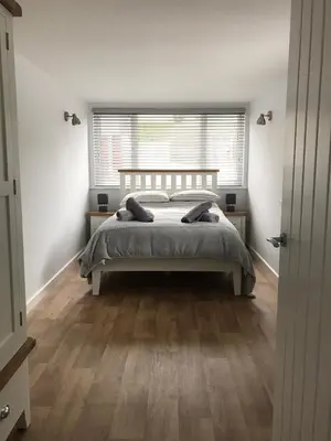 a white bedroom with a bed and a window at Talland Studio in St Ives