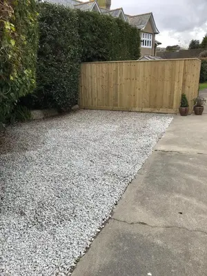 a backyard with a fence and a gravel driveway at Talland Studio in St Ives