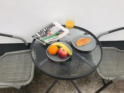 a table with a plate of fruit and a newspaper and a glass of juice at Talland Studio in St Ives