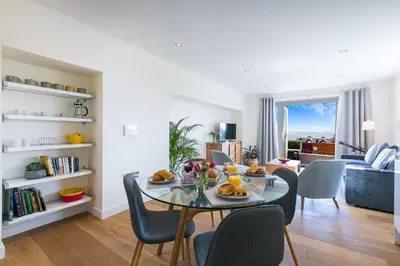 a dining room and living room with a table and chairs at Sea Scapes in St Ives