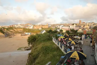 a group of people sitting under umbrellas near a beach at St Christopher's Inn Newquay in Newquay