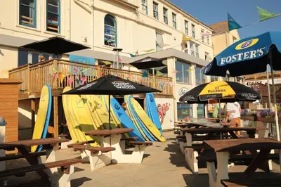 a group of tables with umbrellas and surfboards on them at St Christopher's Inn Newquay in Newquay