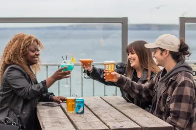 a group of three women holding up drinks at a table at St Christopher's Inn Newquay in Newquay